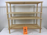 Front view of one wooden shelving unit showing three slatted shelves and four vertical support legs of unfinished light wood.