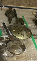 Photo showing two brass bed warmers with perforated lids, a wooden bellows, and a brass matchstick holder arranged on a wooden surface.