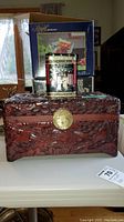 Photo of the carved wooden box with floral and bird designs and the decorative tin can placed on top