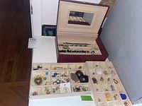 Photo showing maroon jewelry box with lid open displaying assorted costume jewelry in multiple compartments.