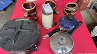 Photo showing large black enamelware pot, 6 brown ceramic soup bowls with handles, an electric coffee grinder, and two small pots (blue and silver)