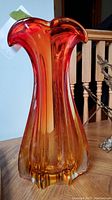 Front angle of the red-orange MCM glass vase showing the flared wavy top and gradual amber coloring at the base
