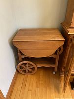 Folded tea cart from the side showing wheels and folding leaf design