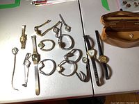 Full lot of 15 watches spread on table, wood box visible on right