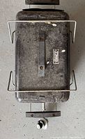 Top view of closed grill lid showing handle, side handles, and Coleman label. The surface is dirty and shows signs of heavy use.