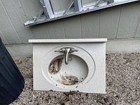 Top view of the oval bathroom sink with faucet showing dirt in basin area.