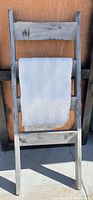 Grey distressed wooden blanket ladder with four rungs leaning against a wall. The ladder shows some rustic wear marks and weathered look. A grey pleated blanket is hanging over the second rung from the top in the first photo.