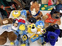 Photo of multiple Colorado sports team plush toys including Denver Broncos, Colorado Rockies, and Denver Nuggets bears, horses, and other characters with team jerseys, hats, and helmets.