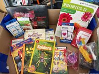 Box of assorted kids items including books, flashcards, workbooks, DVDs, and toys.