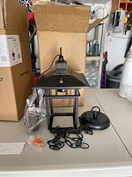 Photo of one unpacked hanging lantern light with components and original open box in background.