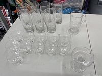 Photo of 7 tall etched crystal Princess House tumblers, 12 dessert cups with handles, 1 Irish coffee cup with handle, and 1 small clear candleholder on a table.