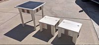 Set of three painted wooden tables, two smaller with hinged tops and one larger with black surface