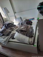 Bed frame with mattress and folded bedding on top, showing overall condition and setup.
