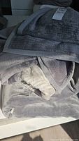 Three plush IKEA blankets folded and stacked, showing some wear and a label on one blanket