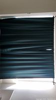 Pair of dark green IKEA drapes hung on a window, showing full coverage with some light passing underneath.