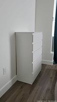 Front and side angled view of the white IKEA dresser near wall and window showing five closed drawers and clean lines.