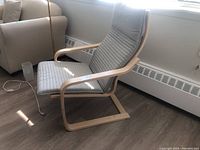 Side view of IKEA Poäng armchair showing wood frame and cushion pad