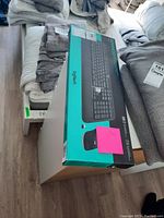 Photo of Logitech wireless keyboard and mouse combo box placed on a white surface with surrounding textiles.