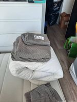 King size duvet folded and stacked with duvet cover on a mattress, neutral colors, fabric with subtle patterns.