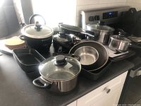 Full view of all pots, pans, baking trays, kettle and accessories on a kitchen counter.