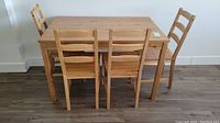 Front view of wood IKEA table with four matching chairs arranged around it.
