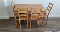 Full view of the rectangular wooden table with four matching chairs arranged around it, showcasing the overall set.