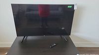 Front view of the 50-inch Fire TV flat screen television on its stand with a remote control placed on the surface in front of it.