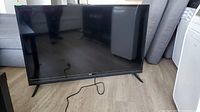 Front view of 50 inch RCA flat-screen television on stand with power cord visible