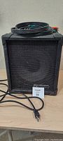 Front view of the black commercial amplifier with audio cables coiled on top.