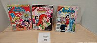 Three Archie Comics comic books displayed upright on a shelf against a plain backdrop. Left to right: Betty and Veronica Double Digest #150, Betty and Veronica Double Digest #165, and Archie Digest Magazine #198.