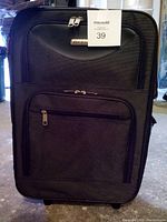 Front view of the black carry-on luggage showcasing size, front zippered pocket, and handle.
