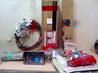 Overall view of the lot showing wreath, boxed Christmas trees, ornaments, wrapping paper, and bows