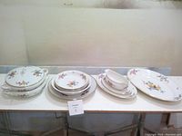 Full view of entire flowered serving set including plates, bowls, and covered dish
