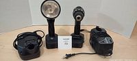 Hitachi cordless drill and handheld light with their chargers placed side by side on a white background.