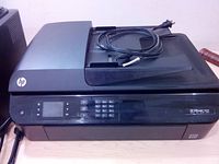 HP Officejet 4630 Printer shown on a table with keypad and control panel visible including cables on top.