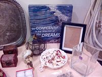 Photo showing old silver tray, brass and wooden items, glass birds, wall art with inspirational quote, small wire basket, shell necklace.