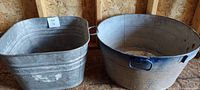 Two vintage galvanized washtubs placed side by side showing overall condition and handles
