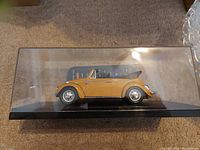 Side view of the 1968 VW Beetle car model inside its clear display case.