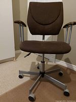 Front view of a dark brown adjustable office chair with silver armrests and caster wheels.