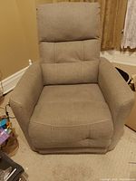 Photo of an electric lift chair upholstered in gray fabric showing cushioned seat, backrest, and armrests with slight visible stitching details.