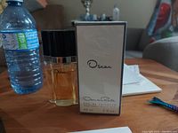 Photo showing one opened bottle of Oscar de la Renta perfume and one unopened boxed bottle.