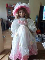Full view of Vanessa Collection porcelain doll in pink and white Victorian-style dress with lace details and matching hat.