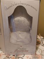 Photo of the wedding dress inside a Prestige Preservation preservation box showing the dress through a transparent window, labeled for long-term memory preservation, sealed as per seller.