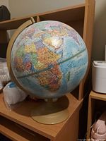 Photo of a world globe highlighting Africa and Europe, showing raised mountain ranges on the land masses which spin on a beige plastic base.