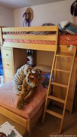 View of the assembled wooden bunk bed with stuffed animals on lower bed and pink linens on both beds.