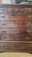 Front view of pine chest showing three small top drawers with knobs and five larger drawers with metal handles below.