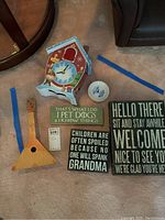 Photo of all items including musical wall clock, wooden string instrument, three plaques, souvenir plate, and small white box.