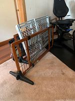 Four baby/pet gates stacked together, including metal mesh and wooden frame gates, showing their adjustable widths and stand bases.
