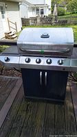 Full front view of Char-Broil 5 burner grill on wooden deck with stainless steel lid and black metal base.