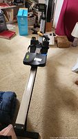 Full length view of rowing machine showing rail, seat, footrests and handlebar